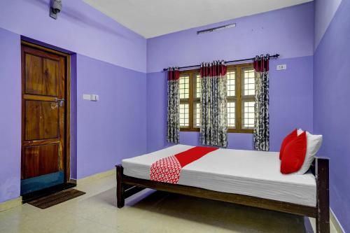 Schlafzimmer mit lila Wänden und einem Bett mit roten Kissen in der Unterkunft OYO Flagship Paradise villa in Cherai Beach