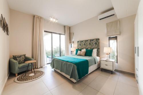 a bedroom with a bed and a chair and a window at Brand new, Beachfront Ocean Terraces, Poste Lafayette-Apt-C2 in Poste Lafayette