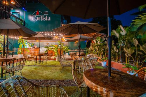 an outdoor restaurant with tables and chairs and umbrellas at LArtista Hostel in Puerto Princesa City