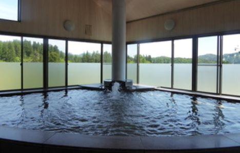 una gran piscina con agua en un edificio con ventanas en 山古志の宿　あまやちの湯, en Minami Uonuma