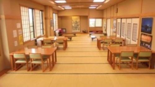 uma sala de aula com mesas e cadeiras num edifício em 山古志の宿　あまやちの湯 em Minami Uonuma
