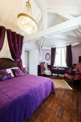 a bedroom with a purple bed and a chandelier at Manoir du Clap in La Cerlangue