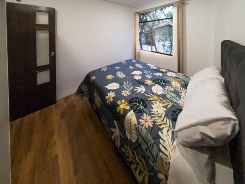 a small bedroom with a bed with a floral blanket at casas de campo para riders in Urubamba