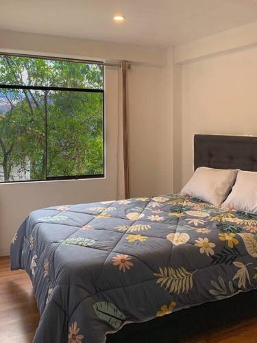 a bedroom with a bed with a blue comforter and a window at casas de campo para riders in Urubamba