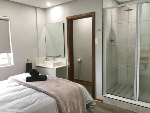 1 dormitorio con ducha, 1 cama y espejo en Beachfront Living at its Finest en Gqeberha