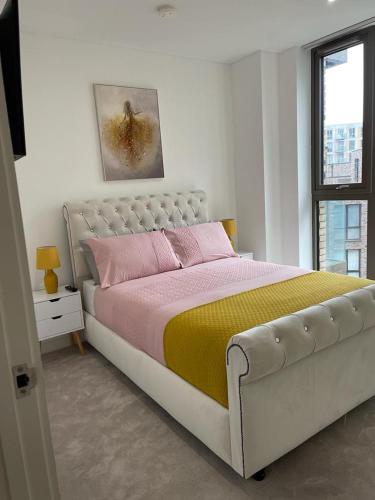 a bedroom with a large bed with pink and yellow sheets at 2bed Royal Wharf London in London