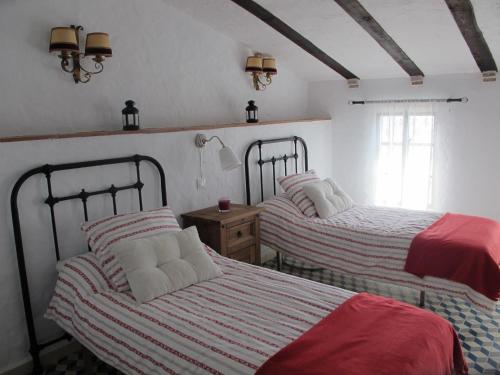 a bedroom with two beds with red and white sheets at Casa Las Torres in Medina de las Torres