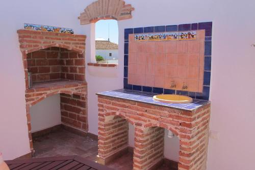 Habitación con chimenea de ladrillo y fregadero. en Casa Las Torres, en Medina de las Torres