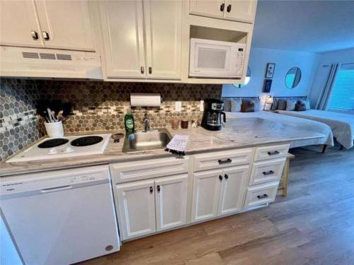 a kitchen with white cabinets and a sink and a bed at Universal-Disney Dream Studio 2 - The Enclave in Orlando