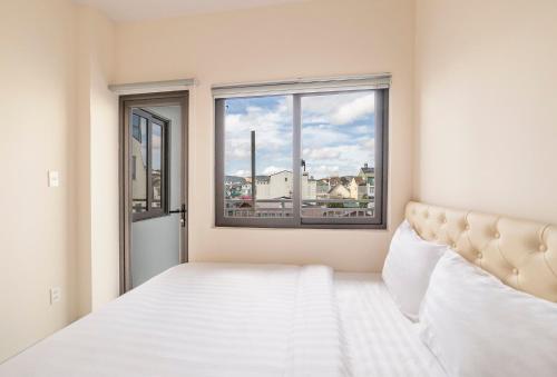 a white bedroom with a bed and a window at Happy Dalat Hotel & Apartment in Da Lat