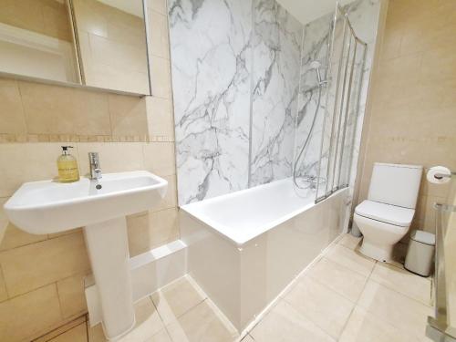 Baño blanco con lavabo y aseo en Hyde Park Elegance Escape : Central & Cozy, en Londres