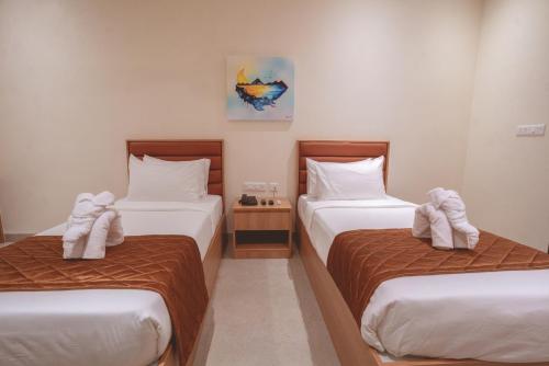 a bedroom with two beds with towels on them at HOTEL ACHYUT in Tiruppūr