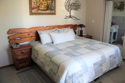 a bedroom with a large bed with a wooden headboard at The Sun Catcher B&B in Struisbaai