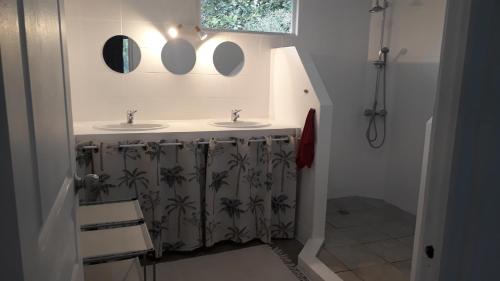Baño con 2 lavabos y espejos en la pared en Maison a 5mn de Teahupoo Tahiti Polynesie FR, en Tohautu