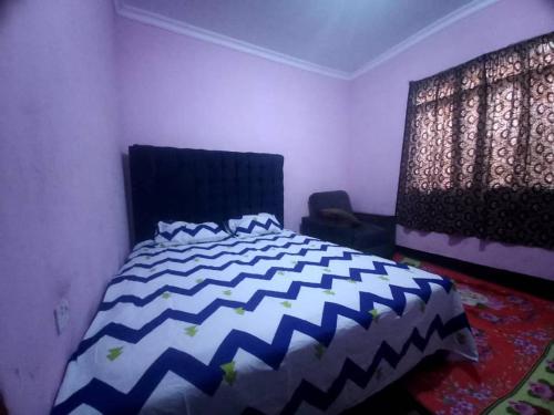 um quarto com uma cama azul e branca e uma janela em Bright Backpackers home stay em Mwanza
