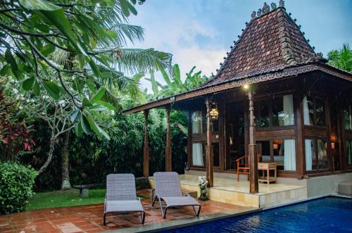 une maison avec deux chaises et une piscine dans l'établissement Ubud Heaven Penestanan, à Ubud