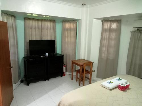 Schlafzimmer mit einem Bett, einem TV und einem Tisch in der Unterkunft Larot's Vacation House - Rooms Only in Siquijor