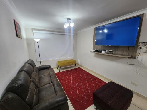 een woonkamer met een bank en een grote tv bij rodrich business apartment in Lima