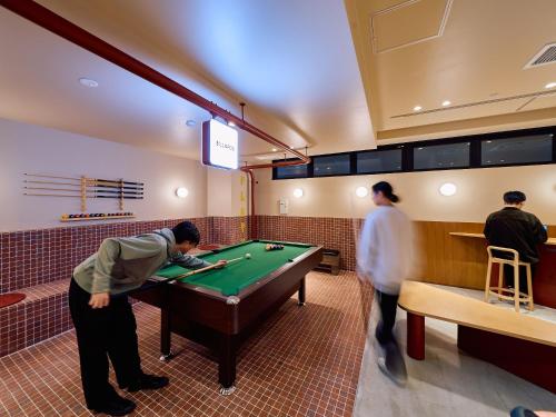a group of men playing pool in a billiard room at Hotel Plus Hostel TOKYO ASAKUSA 2 in Tokyo