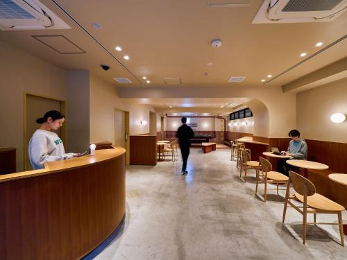 mężczyzna i kobieta stojący przy ladzie w restauracji w obiekcie Hotel Plus Hostel TOKYO ASAKUSA 2 w Tokio