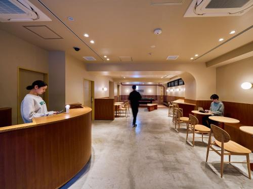 a man and a woman standing at a counter in a restaurant at Hotel Plus Hostel TOKYO ASAKUSA 2 in Tokyo