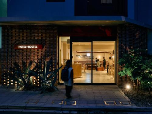 a person walking outside of a store at night at Hotel Plus Hostel TOKYO ASAKUSA 2 in Tokyo