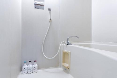 Baño blanco con ducha y botellas en el suelo en Tokyo Skytree Residence Inn (F2) en Tokio