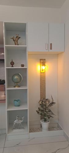 a white book shelf with a plant in a room at 1 bhk luxury flat in Trivandrum