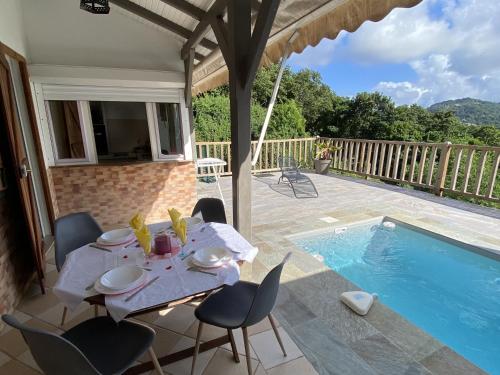 a dining table and chairs next to a swimming pool at Appartement T2 B - vue campagne in Le Robert