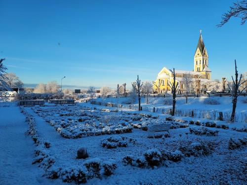 a garden covered in snow with a church in the background at Hoby Gård B&B in Bräkne-Hoby