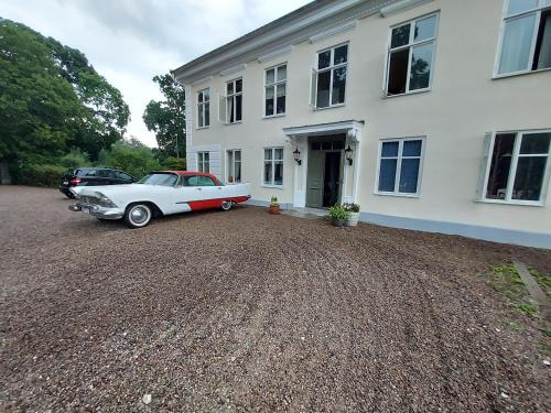 a white car parked in front of a white house at Hoby Gård B&B in Bräkne-Hoby
