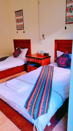 2 camas en una habitación con 2 mesitas de noche en 天堂鸟花园客栈, en Luang Prabang