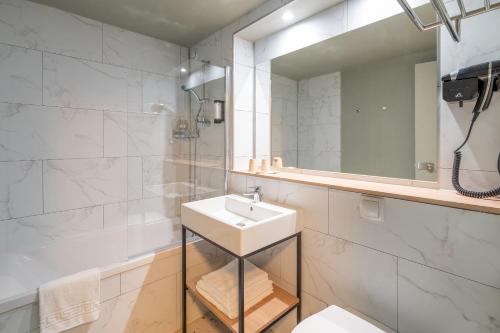 a bathroom with a sink and a shower and a mirror at Sure Hotel by Best Western Rochefort-sur-Mer in Tonnay-Charente