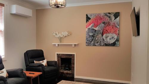 a living room with a fireplace and a painting on the wall at Kangaroo Island Seabright Garden Cottage in Kingscote