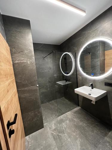 La salle de bains est pourvue d'un lavabo et d'une douche avec un miroir. dans l'établissement Mountain Home Alpendorf, à Plankenau