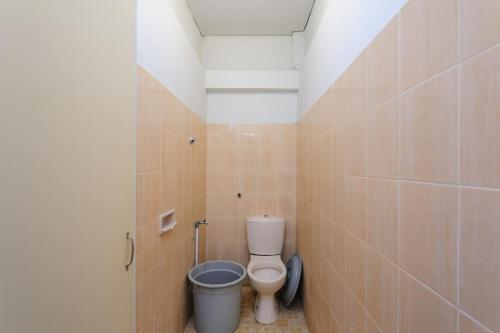 a bathroom with a toilet and a trash can at RedDoorz Syariah @ Panglima Nyak Makam Aceh 2 in Banda Aceh