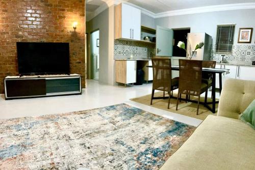 uma sala de estar com um sofá, uma mesa e uma cozinha em The Comfy Corner @ Skyfall Country Estate em Polokwane