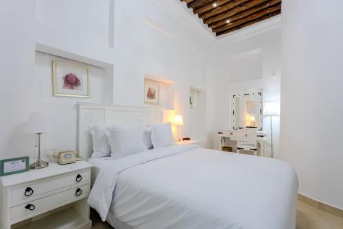 a white bedroom with a white bed and a table at Arabian Boutique Hotel in Dubai
