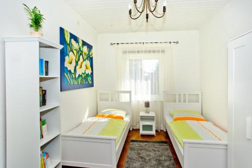 two beds in a white room with a chandelier at NEU! Ferienwohnung Zum Kaminzimmer in Toppenstedt
