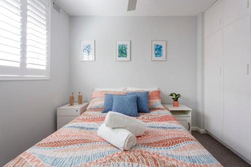 una camera bianca con un grande letto con cuscini blu di East Fremantle Escape a Fremantle