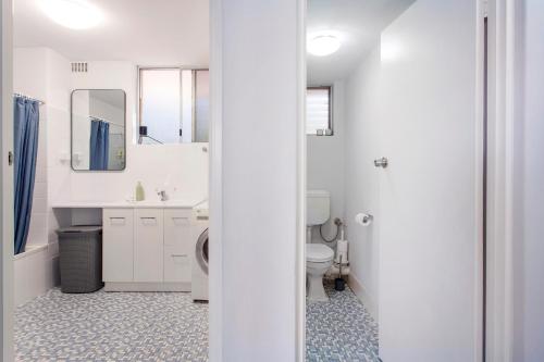 La salle de bains blanche est pourvue de toilettes et d'un lavabo. dans l'établissement East Fremantle Escape, à Fremantle