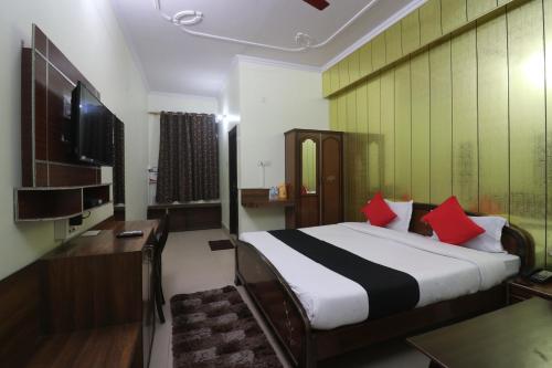 a bedroom with a bed and a desk and a television at Hotel Mandakini in Rudraprayāg