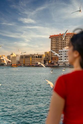 a woman looking at birds flying over the water at Arabian Boutique Hotel in Dubai
