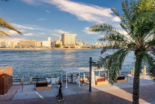 a man walking on a boat on the water with a palm tree at Arabian Boutique Hotel in Dubai