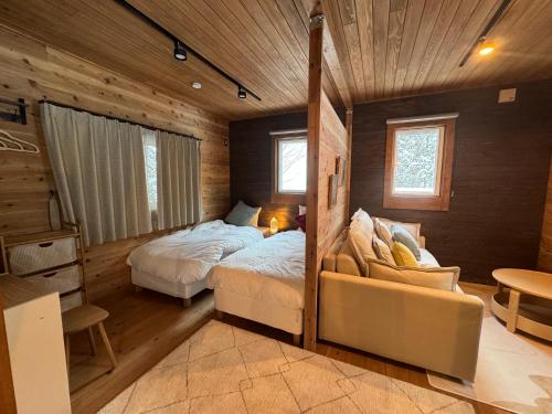 ein Schlafzimmer mit zwei Betten und einem Sofa darin in der Unterkunft 美瑛森林木屋 - 小紅帽 in Biei