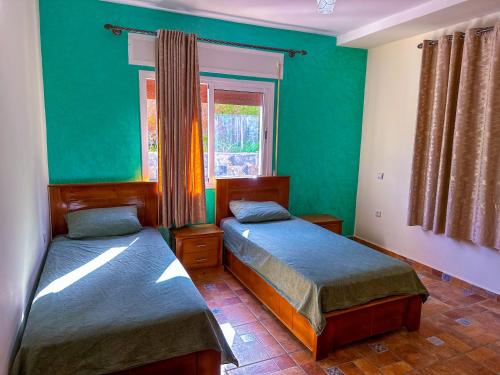 Cette chambre comprend 2 lits dans une chambre dotée de murs verts et d'une fenêtre. dans l'établissement Luxury duplex with private pool - Sea view and Fast wifi, à Oued Laou