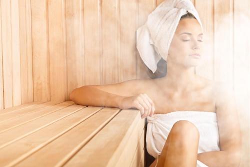 a woman sitting in a sauna with a towel on her head at AirbnbTřeboň - modern apartment in Třeboň