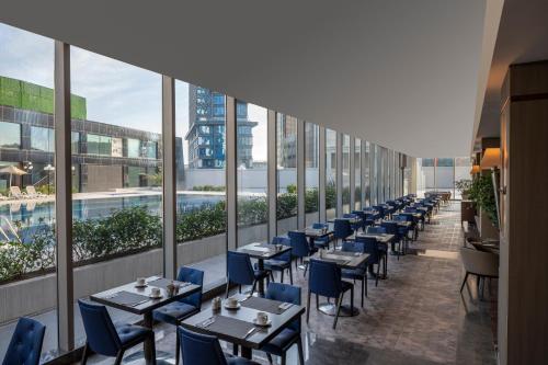 a row of tables and chairs in a restaurant with windows at Windsor Hotel & Convention Center Istanbul in Istanbul