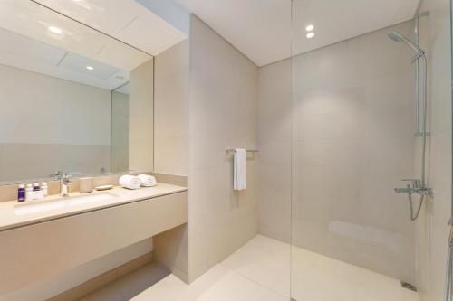 ein Bad mit einem Waschbecken und einer Dusche in der Unterkunft Maison Privee - Exquisite Apt on Yas Island cls to ALL attractions in Abu Dhabi