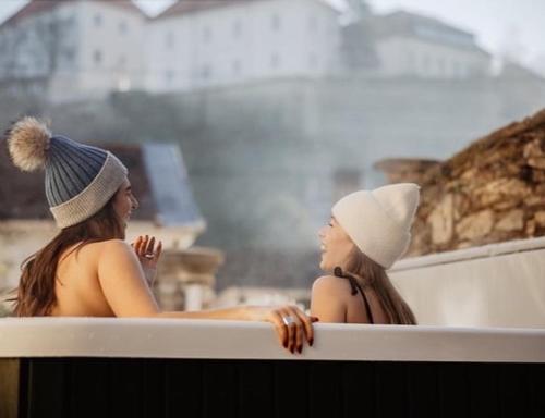 two women are sitting in a bath tub at FRIDA Apartman, Exkluzív várpanorámával, a belváros szívében in Veszprém